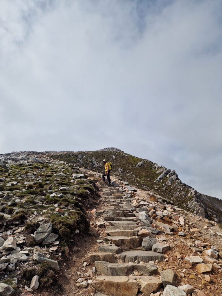 Vyras lipa laiptuotu taku į Errigal kalno viršūnę Airijoje